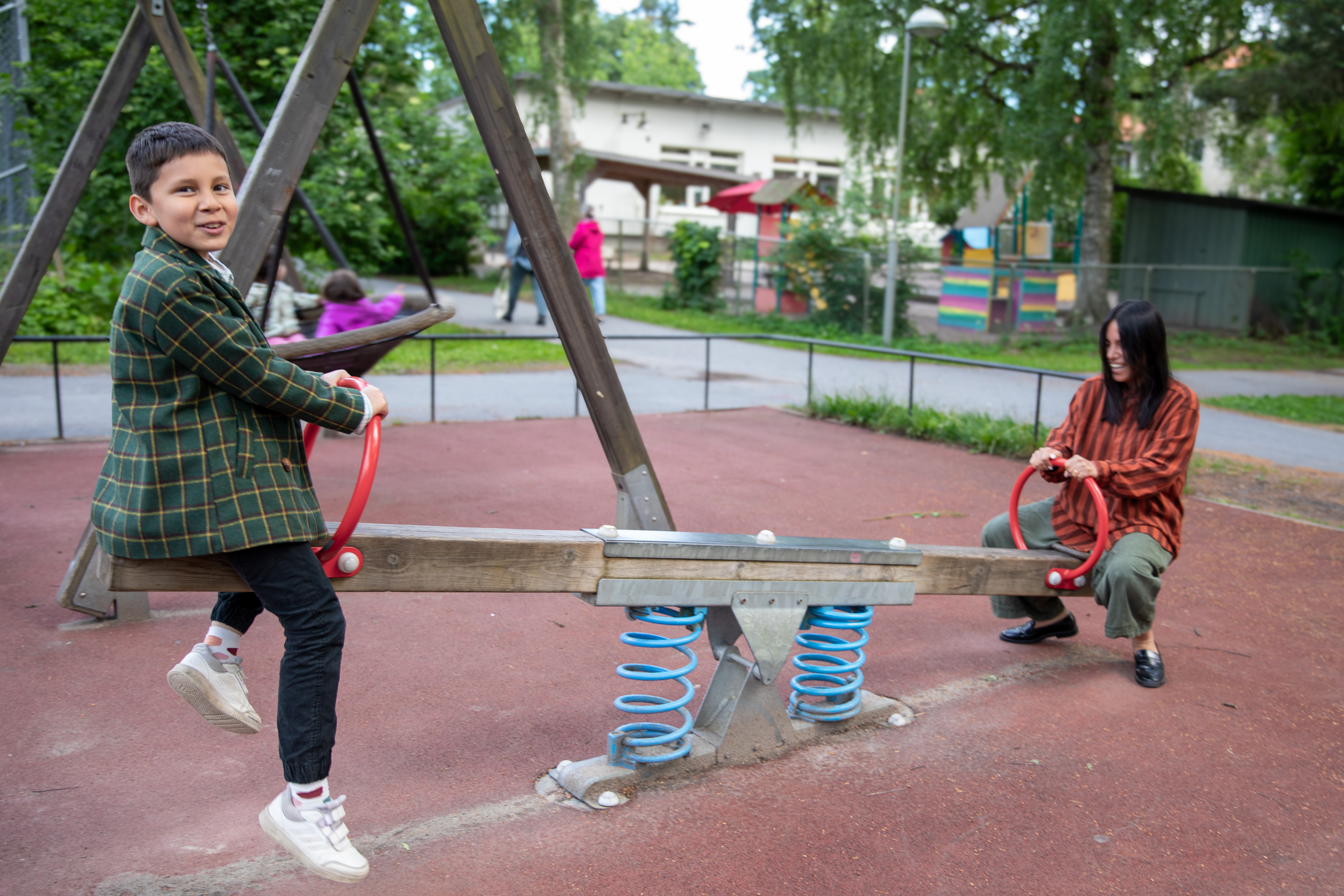 En pojke gungar på en gungbräda med en förälder