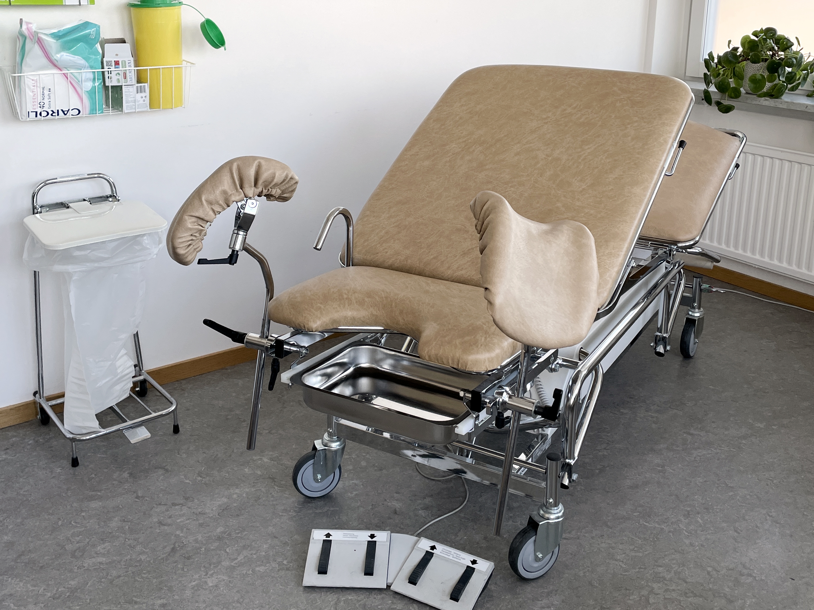 Ett undersökningsrum och en gynstol. I bakgrunden syns ett bås där man kan klä av sig på underkroppen.