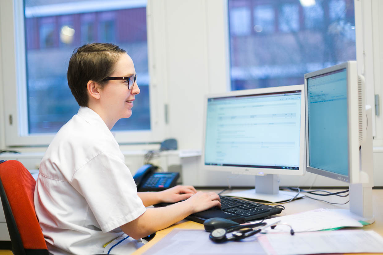 Vårperson sitter och tittar på en bildskärm vid ett skrivbord.