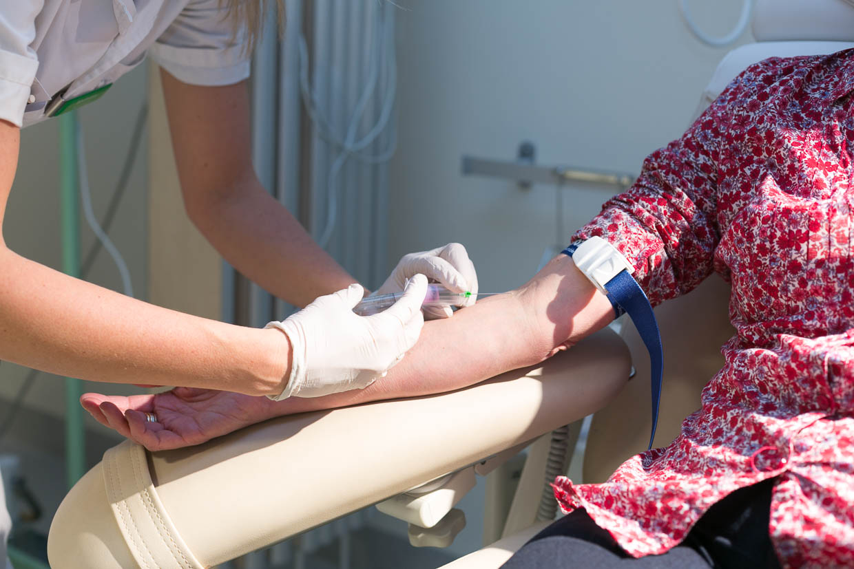 En vårdperson sätter en nål i armen på en patient som sitter ner.